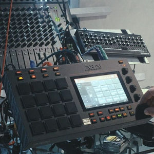 Akai MPC Live in the foreground of the Zombie Nation studio with a mixing desk and synthesizers behind