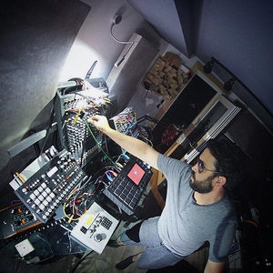 Producer reaching over a mixing desk with drum machines and synthesizers, photographed in fisheye