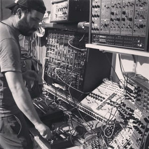 Producer seen from the side operating a large modular synthesizer system, photographed in black and white
