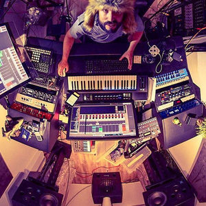 Overhead fisheye view of the studio with a producer at the centre, ringed by synthesizers and gear