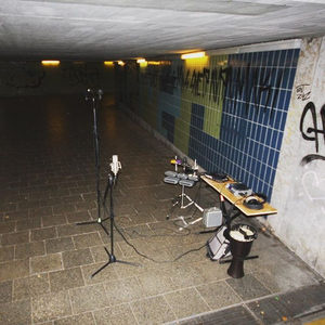 A microphone stand and recording equipment set up alone in a graffiti-lined urban underpass at night