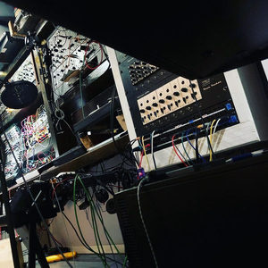 Looking up from beneath the Zombie Nation studio desk at tangled cables, synthesizer modules and a monitor