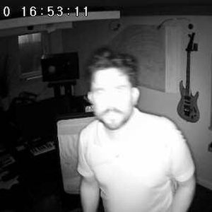 CCTV still from the Zombie Nation studio, timestamp 2019/07/10, monochrome with guitar visible on the wall