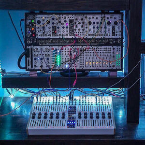 Zombie Nation Eurorack modular rack in blue light with patch cables, step sequencer controller on the desk