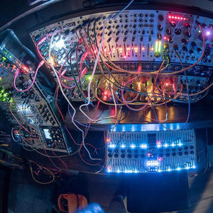 Overhead fisheye of a Zombie Nation Eurorack modular with colorful patch cables and a backlit keyboard at