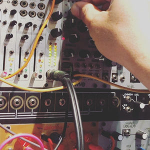 Hands connecting patch cables to a Zombie Nation Eurorack modular rack with WMD mixer module and colorful