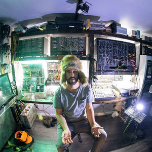 Fisheye portrait in the Zombie Nation studio, fur hat, modular synthesizers and hardware packed around the