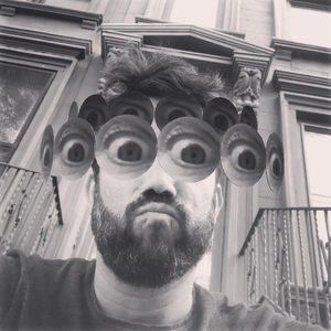 Humorous selfie with multiple eyes added by a face filter, black and white, ornate building facade in the