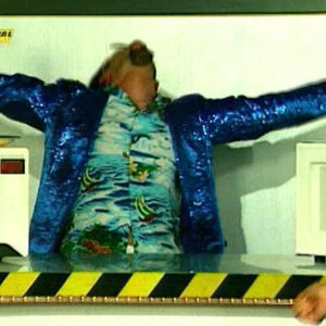 Zombie Nation Kernkraft 400 official music video screenshot, performer in a blue sequin jacket on a TV