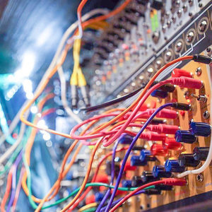 Side angle of a large Zombie Nation modular rack densely patched with pink patch cables, close-up view