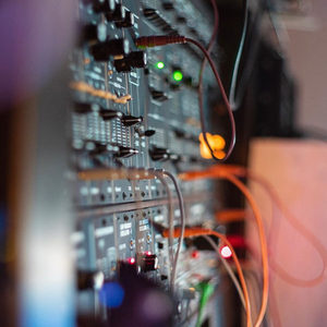 Side angle of a Zombie Nation modular synthesizer rack, shallow depth of field, orange cable and red