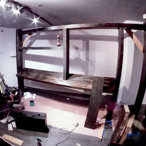 Zombie Nation studio desk with Akai MPC Live and a custom wood panel being fitted behind it, hand in frame