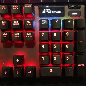 SteelSeries Apex 7 mechanical keyboard with red backlighting and Bitwig logo on the OLED display screen