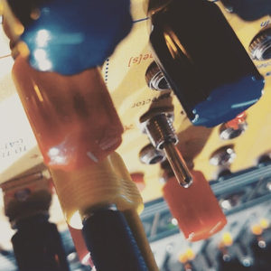Extreme close-up of a yellow Eurorack module, blue banana jacks with orange and tan cables plugged in