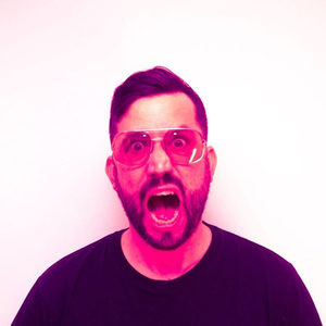 Florian Senfter in a magenta-tinted portrait, round clear-frame glasses, mouth open in an expressive pose
