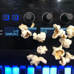 Popcorn scattered on an Elektron Digitakt, LCD displaying TEMPLATI 1/2, blue step buttons along the bottom