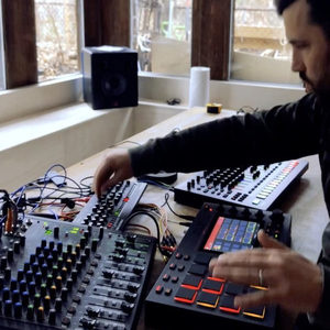 Producer at a trestle desk with a Mackie ProFX mixer and Akai MPC Live in a loft space by large windows